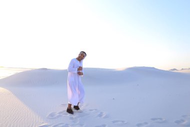 Kendine güvenen erkek yakışıklı Arap Kandur içinde beyaz ortasında yürüyor