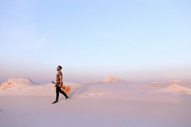 Dese aracılığıyla elinde gitar ile görkemli Müslüman genç adam yürüyor