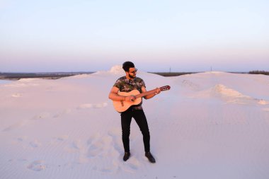 Gitar ayakta bottomle ortasında oynayan yakışıklı erkek Arap