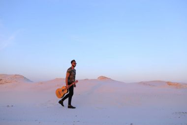 Dese aracılığıyla elinde gitar ile görkemli Müslüman genç adam yürüyor