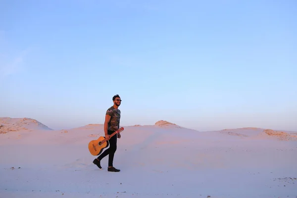 Stattliche muslimische junge Mann geht mit Gitarre in den Händen durch dese — Stockfoto