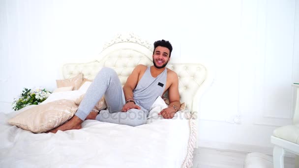 Portret van mannelijke moslim vakantieganger van stad drukte op Bed in lichte slaapkamer. — Stockvideo
