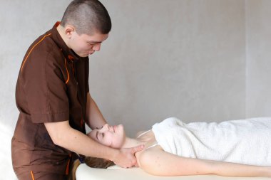 Adam masör güçlü elleriyle yalan genç kız, boyun kneads