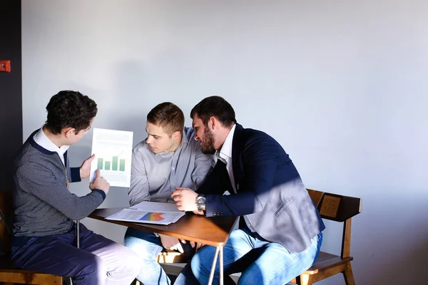 Trzech młodych mężczyzn programistów komunikować się za pomocą tabletu podczas sitt — Zdjęcie stockowe