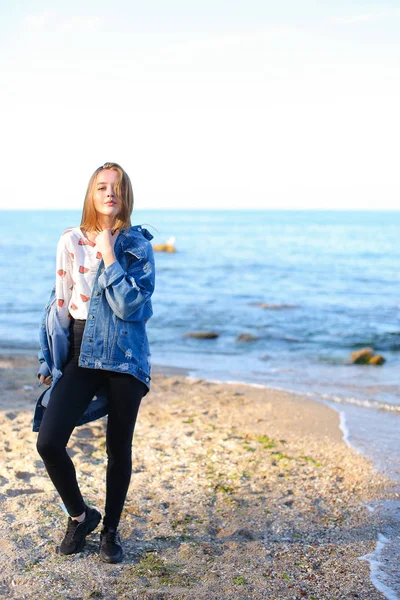 Çekici kız sahil boyunca yürür ve neşeyle kum üzerinde aptallar