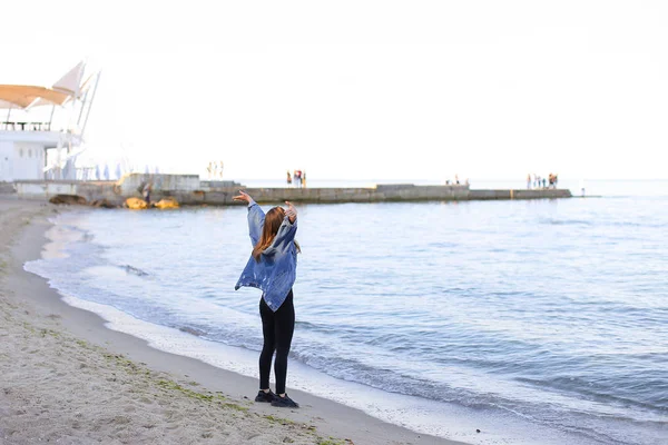 Очаровательная девушка идет вдоль берега и веселые дураки вокруг на песке — стоковое фото