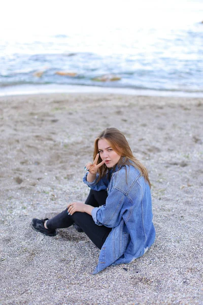 Belle fille se reposant, assis par la mer et posant sur la caméra sur b — Photo