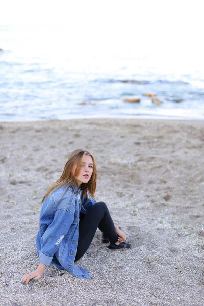 Dinlenme, deniz kenarında oturan ve b kameraya poz güzel kız — Stok fotoğraf