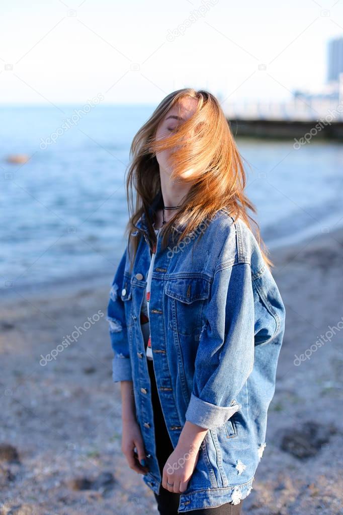 Happy young female develops hair and poses on camera, standing o