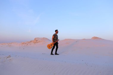 Dese aracılığıyla elinde gitar ile görkemli Müslüman genç adam yürüyor