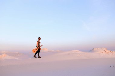 Dese aracılığıyla elinde gitar ile görkemli Müslüman genç adam yürüyor