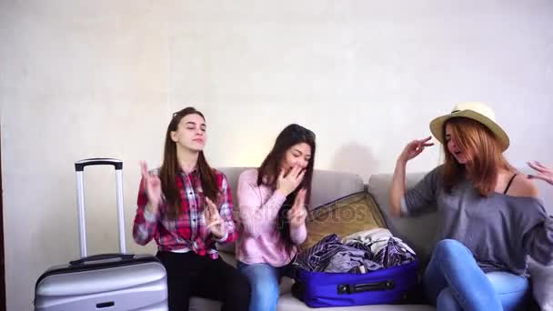 Female girls going on trip and preparing luggage on couch in afternoon room. — Stock Video