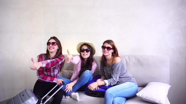 Красиві дівчата збираються в подорож і готують валізи на дивані в другій кімнаті . — стокове відео