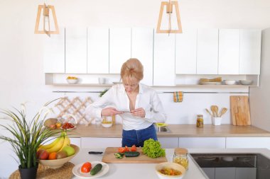 Mutfak kız smartphone elinde tutan ve sebze fotoğrafı çeker