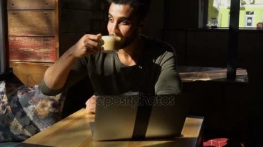 dizüstü bilgisayar ile rahat kafe toplantısı için bekleyen genç adam
