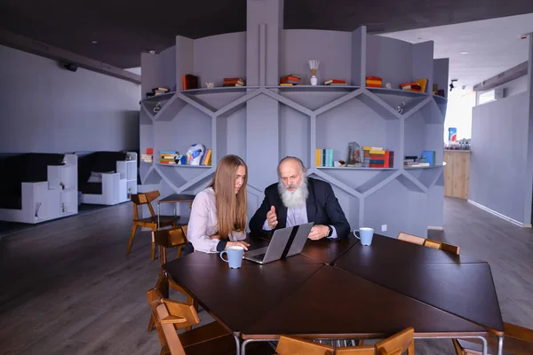 Businesswoman using laptop with old man colleague in successful