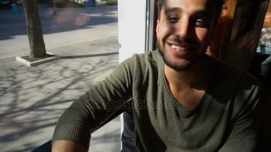 Arap yakışıklı gülümser ve Göz kırpmalar Cafe.