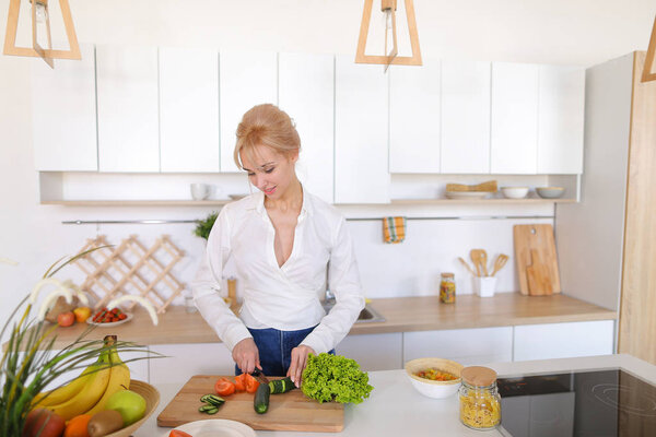 Красивая девушка готовит салат из свежих овощей на доске
