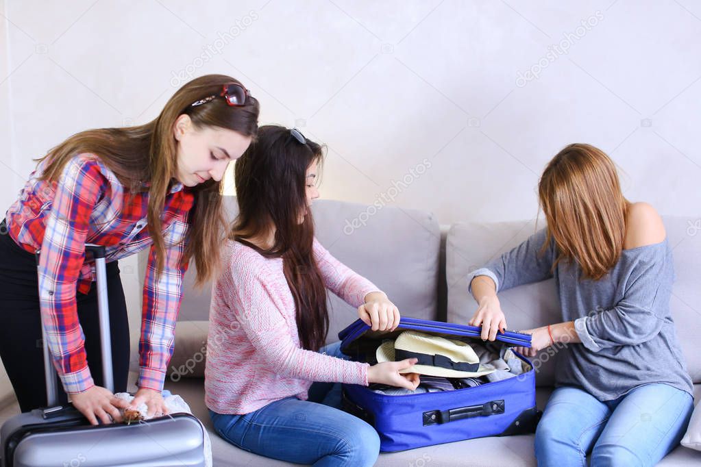 Cute girls going on trip and preparing suitcases on couch in aft