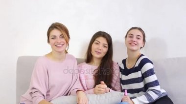 Üç çekici genç arkadaşlar kamera gülümsüyor ve parlak yatak odasında kanepede oturan ile poz.