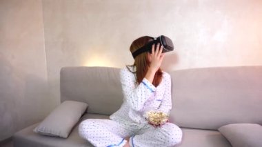 Serin kız video akşamları parlak yatak odasında kanepede oturan Vr bardaklarda saatler.