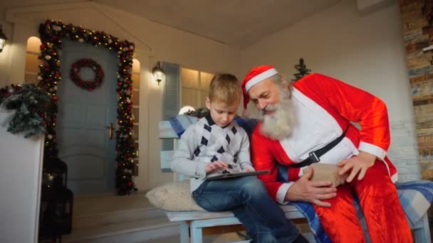 Lycklig pojke får tablett från jultomten. — Stockvideo