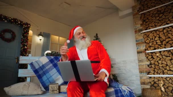 Lustige Weihnachtsmänner, die Daumen hoch zeigen und mit Laptop arbeiten. — Stockvideo