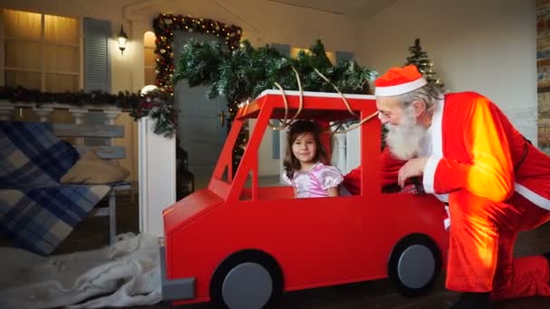 Funny Santa Claus jugando con pequeños príncipes saludando mano en coche rojo . — Vídeos de Stock