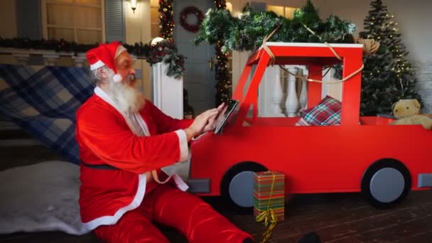 Cheerful Father Christmas preparing gift with tablet. — Stock Video