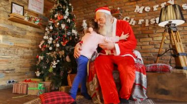 Küçük kız Noel Baba ve gülümseyerek mutlu bir şekilde hugs.