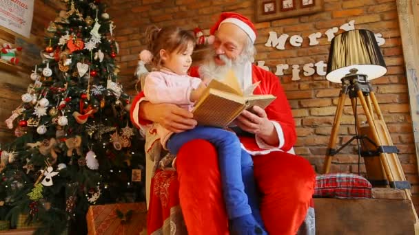 Papá Noel sentado en la silla y sosteniendo a la niña — Vídeo de stock