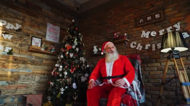 Petit enfant court au Père Noël, s'assoit sur les genoux et fait un vœu, assis sur une chaise décorée dans une salle de fête — Video