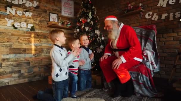 Рідні брати хлопчики колядує до Санта-Клауса в залі, оформленому у свята — стокове відео