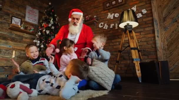 Веселый Санта и веселые мальчики и девочка дать пять друг другу в комнате украшены праздники — стоковое видео