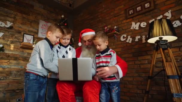Веселі хлопці друзі запобігти замовлення подарунків на ноутбуці в кімната оформлена на Різдво Санта-Клауса — стокове відео