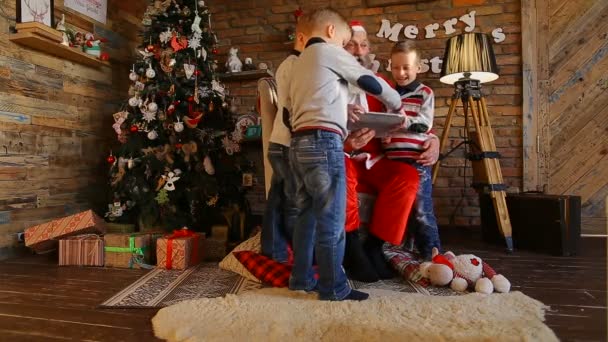 Drei aktive Jungen der Brüder, zusammen mit Vater Weihnachten, schreiben E-Mail in Laptop in dekorierten Raum am Vorabend — Stockvideo