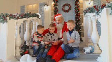 Mutlu erkek çocuk ev Noel süsleri ve yeşil Noel ağacı ile verandada Noel Baba yeni yıl hediyesi ile mutlu