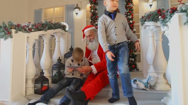 Παππού Χριστούγεννα και χαριτωμένο αγόρι κάθεται στην πόρτα του σπιτιού και χρησιμοποιούν tablet με περιέργεια — Αρχείο Βίντεο