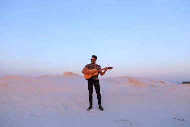 Gitar ayakta bottomle ortasında oynayan yakışıklı erkek Arap