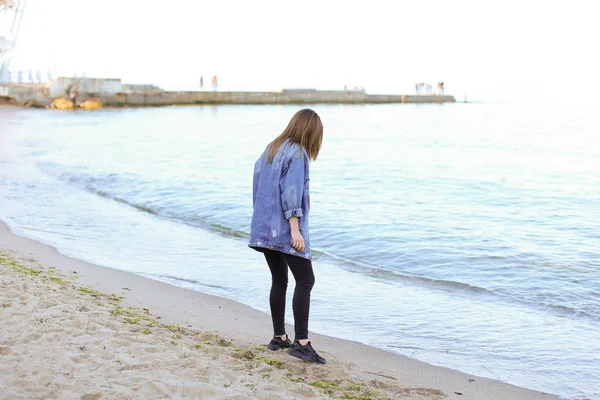 Pretty woman smiles easily and looks at horizon, standing on sho — Stock Photo, Image