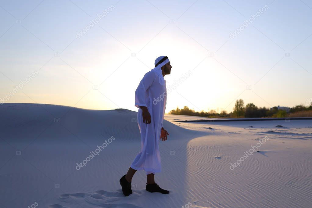 Confident male handsome Arab in Kandur walks in middle of white