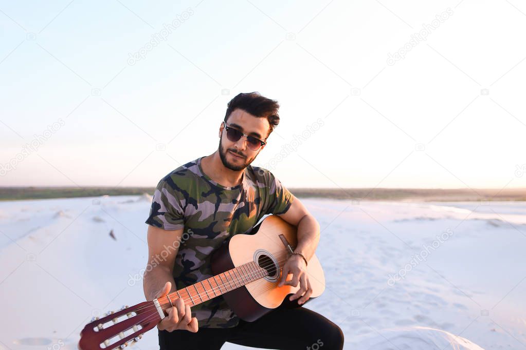 Portrait of young Muslim man who plays music on guitar among san