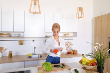 Akıllı kız dilim salatalık gülümser, ki ayakta ve bıçak ile