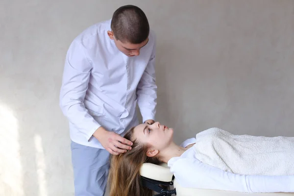 Красивый парень массажист делает массаж головы для девушки. — стоковое фото