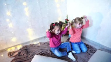 Aktif küçük çocuklar kız gülmek ve Road'daki, zemin ve duvar garland ve öğleden sonra Noel ağacı ile çerçevede halı oturan.