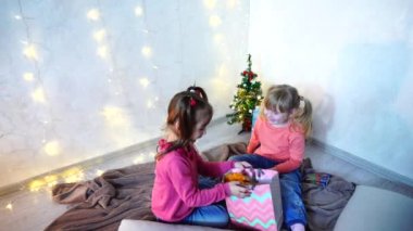 Aktif küçük çocuklar kız gülmek ve Road'daki, zemin ve duvar garland ve öğleden sonra Noel ağacı ile çerçevede halı oturan.