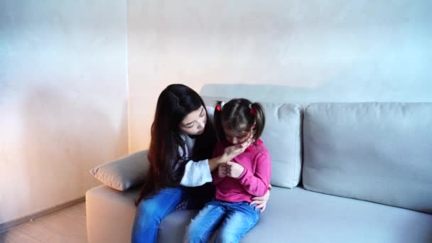 Bela jovem mãe e filha sentada no sofá . — Vídeo de Stock