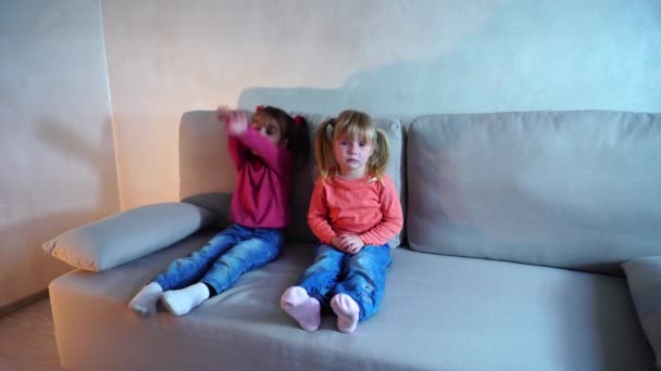Dwie siostry, siedząc na kanapie, mała dziewczynka płacze. — Wideo stockowe