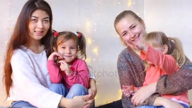 Genç anne küçük kızları ile zemin ve aile albümü için kamera poz oturmak.