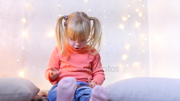 Menina senta-se no chão no quarto com decoração de Natal e joga jogo no telefone . — Vídeo de Stock